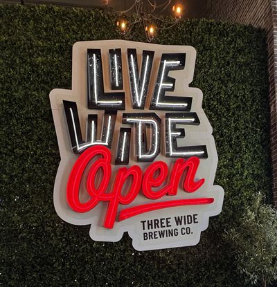 Indoor electrical sign reading Live Wide Open, Three Wide Brewing Co.