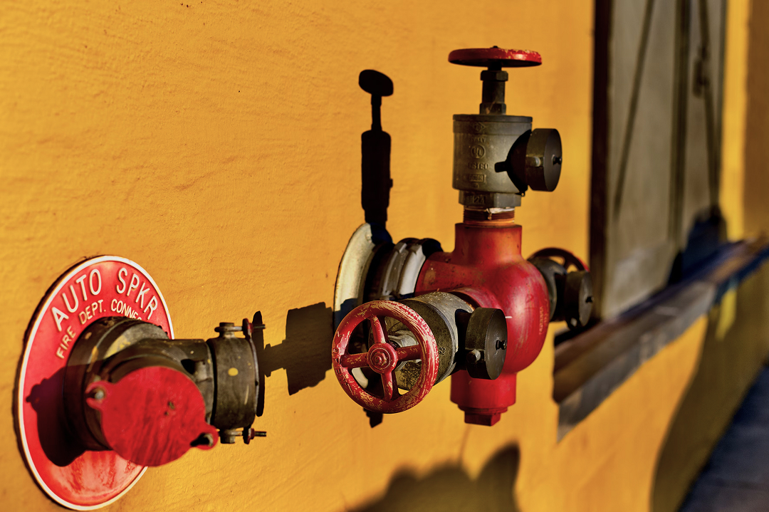 Fire sprinkler connection attached to yellow wall